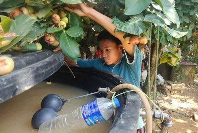 Mohd Nabil menunjukkan tong air yang mengandungi air telaga keruh yang disedut naik melalui paip.