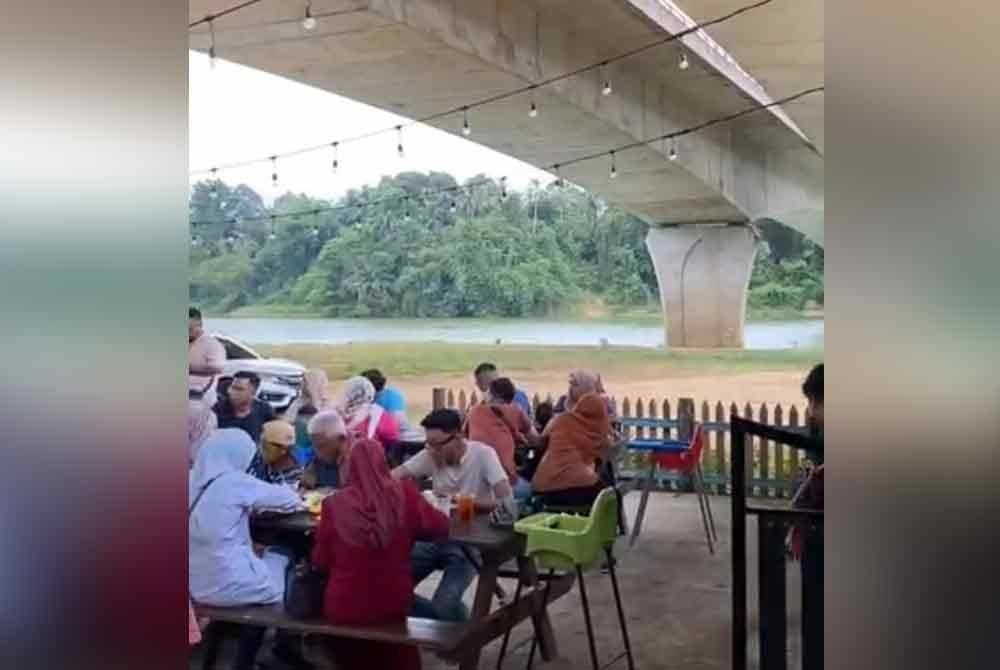 Pelanggan menikmati makanan di tepi sungai.
