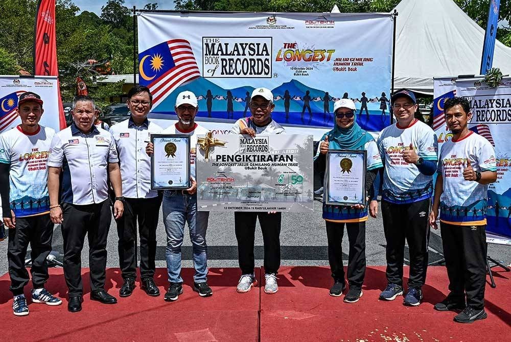 Pegawai Daerah Dungun, Jusman Ibrahim, bersama Pengarah Politeknik Sultan Mizan Zainal Abidin (PSMZA), Zamra Derahman, Pengurus Besar PETRONAS Wilayah Timur, Mohamad Ahmad Shazly Ramli, dan Pegawai Malaysia Book of Records, Edwin Yeoh Tiong Chin, mempamerkan sijil pengiktirafan Malaysia Book of Records dalam program The Longest Jalur Gemilang Human Trail @ Bukit Bauk, hari ini.