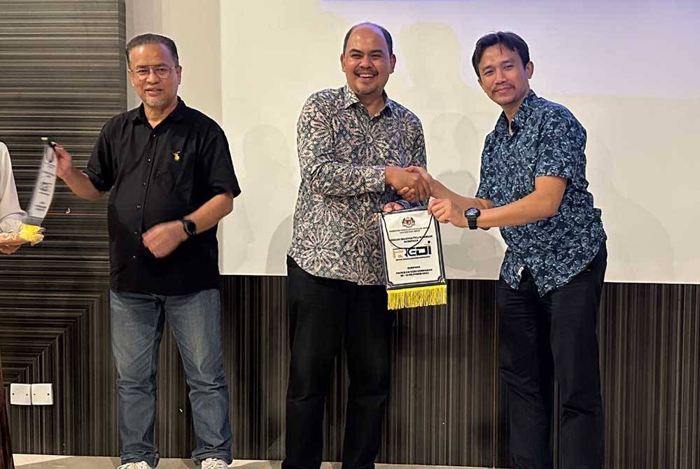 Azman (kiri) mengiringi Muhamad Hanif (tengah) bagi menyampaikan cenderamata kepada rakan strategik ReDI.