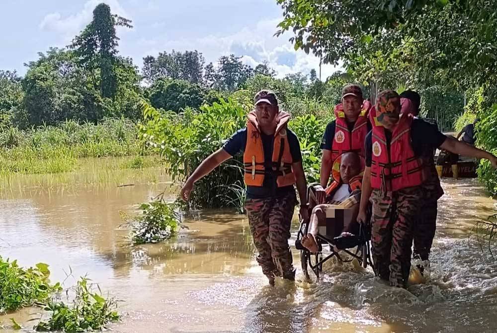 Anggota bomba memindahkan seorang warga emas yang terjejas banjir di Baling. Foto JBPM