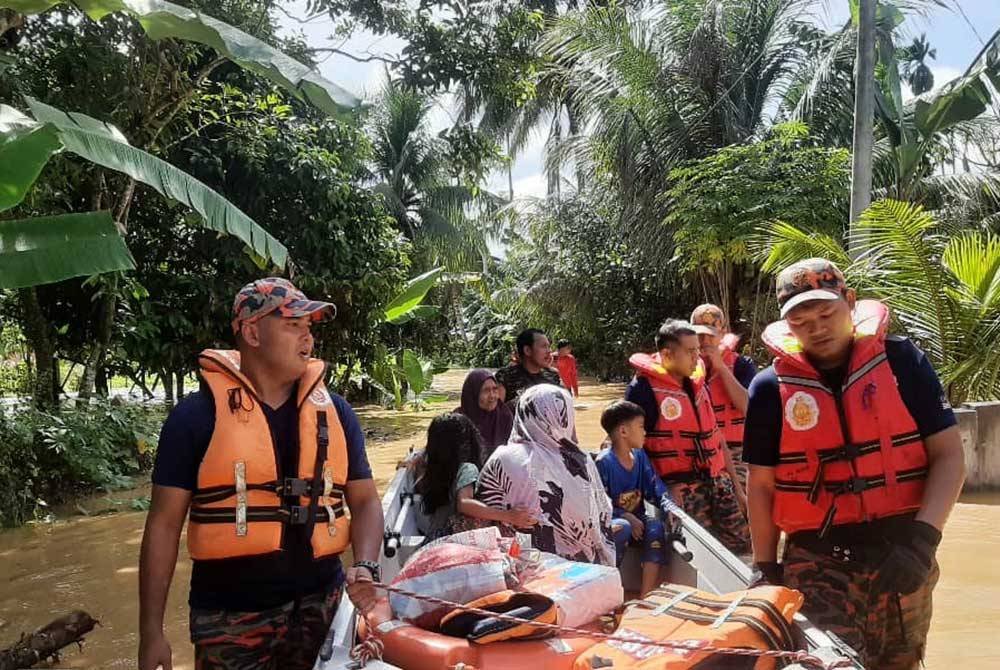 Anggota bomba memindahkan mangsa terjejas banjir di daerah Baling. Foto JBPM
