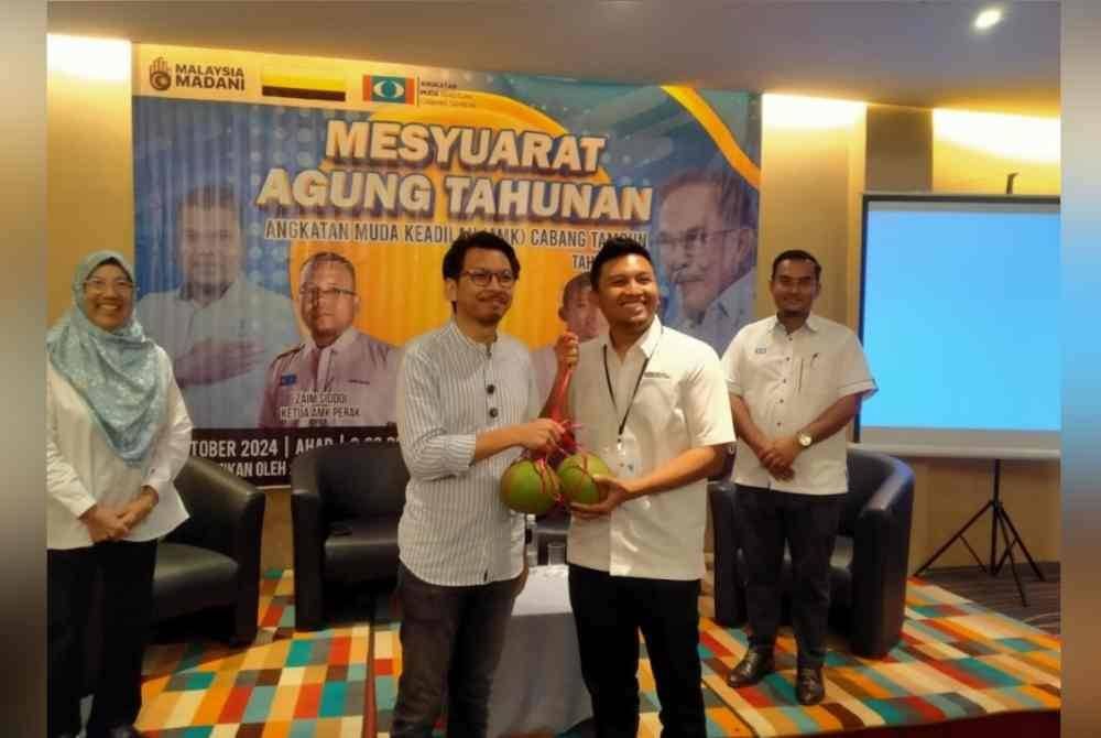 Muhammad Kamil (kiri) menerima cenderahati daripada Ketua AMK Cabang Tambun, Ashraf Kahasani selepas merasmikan Mesyuarat Agung Tahunan AMK Cabang Tambun di sebuah hotel di Bandar Meru Raya di sini pada Ahad.