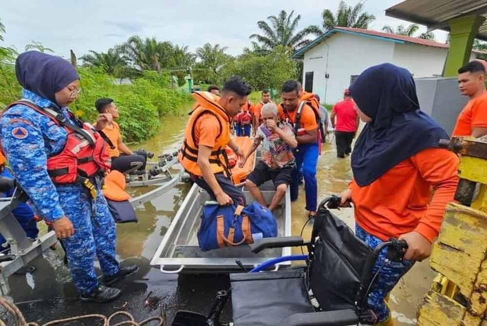 Seorang warga emas dipindahkan ke tempat selamat setelah rumah mangsa dinaiki air. FOTO APM