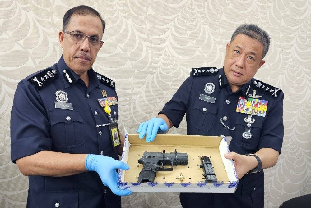 Azizi bersama Timbalannya, Deputi Komisioner Zulkafli Sariaat menunjukkan pistol yang dirampas daripada suspek.