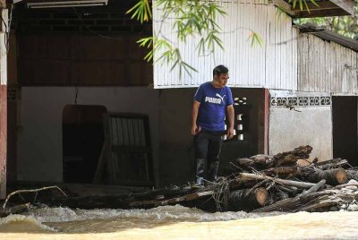 Halaman rumah Mohd Naim telah berubah menjadi laluan sungai kecil setelah banjir melanda di Kampung Teluk Rambong pada Sabtu - Foto: Bernama