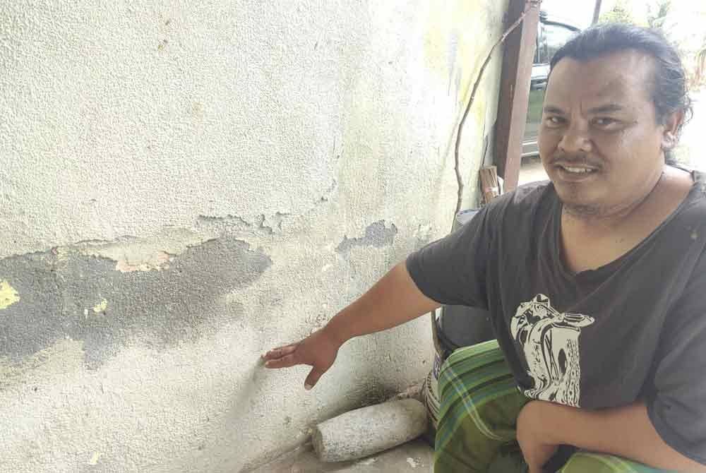 Muhammad Riduan menunjukkan paras air laut yang memasuki rumahnya di Kampung Baru Lembah Pantai, Sungai Kajang, Tanjong Karang di sini.