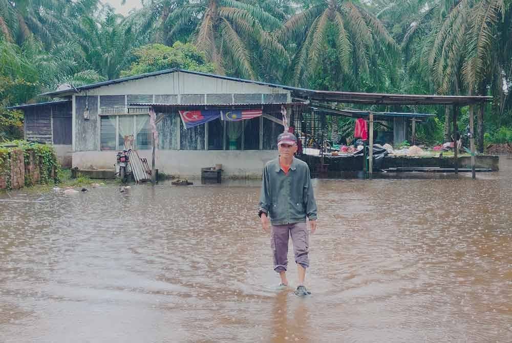 Mohamad meredah banjir termenung di halaman rumahnya di Kampung Talang Bunut.