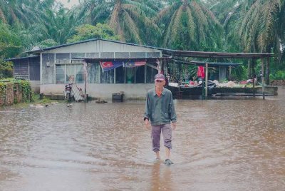 Mohamad meredah banjir termenung di halaman rumahnya di Kampung Talang Bunut.
