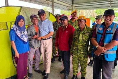 Ahli Dewan Undangan Negeri (ADUN) Semarang, Datuk Samsolbari Jamali (tiga, kiri) menyantuni mangsa banjir Mohamad Ibrahim (dua, kiri) dan keluarganya serta petugas di PPS Sekolah Kebangsaan Seri Bunut pada Selasa. Foto Bernama