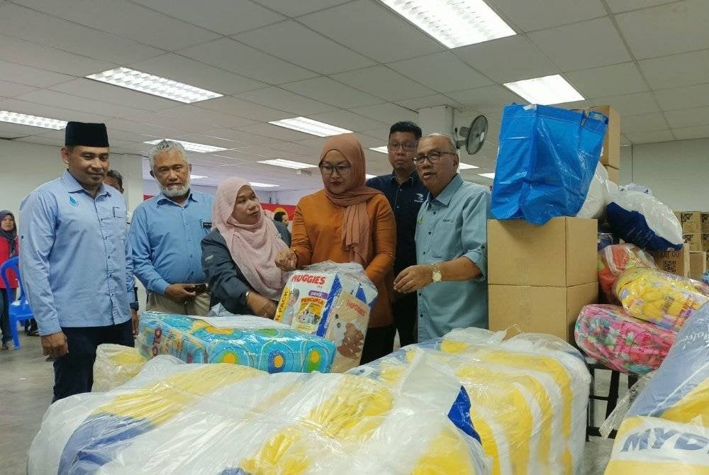 Mohd Zolkafly (kanan) menunjukkan pelbagai barangan keperluan dan bantuan untuk diberikan kepada mangsa banjir di kawasan DUN Lintang.