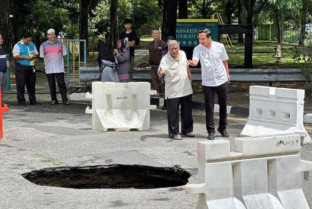 Fahmi (kanan) meninjau kejadian lubang benam di Taman Sri Nibong yang berlaku pada Rabu.