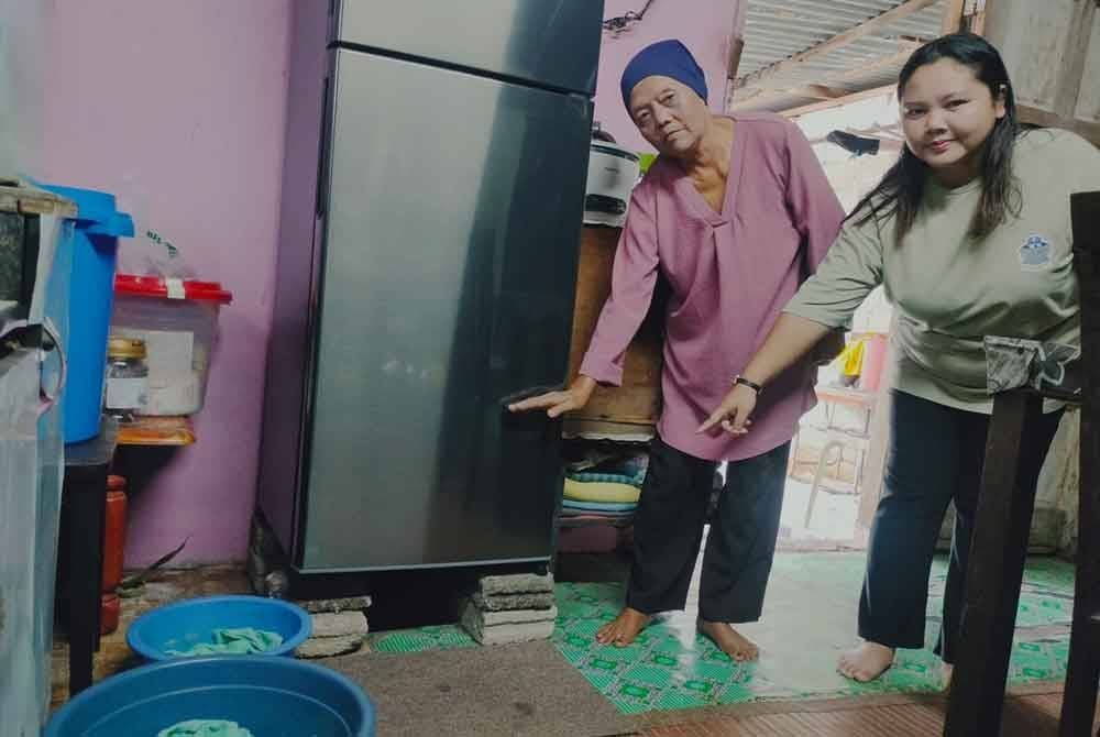 Zubaidah (kiri) dan Siti Norziana (kanan) menunjukkan rumah yang dikemas dan peti ais diletakkan lebih tinggi dengan batu di Kampung Kebun Baru Sungai Durian, Kukup Pontian.