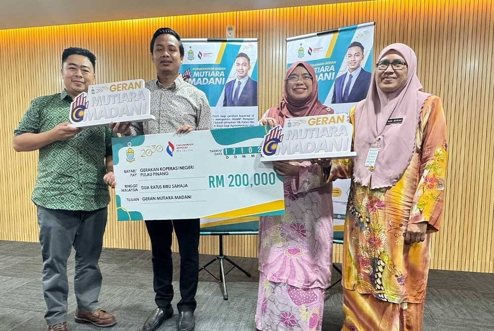 Fahmi (dua dari kiri) memegang replika cek Geran Mutiara Madani Koperasi Pulau Pinang yang diserahkan kepada Pengarah Suruhanjaya Koperasi Malaysia (SKM) Cawangan Pulau Pinang, Zainab A Raman (dua dari kanan) di Komtar pada Khamis.