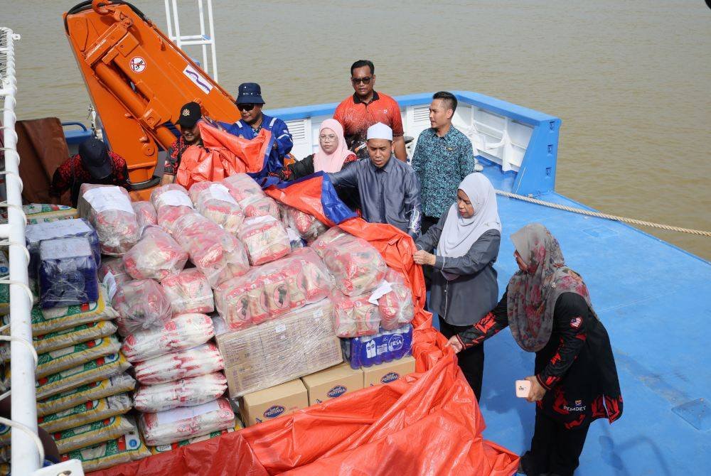 Mazura (dua dari kanan) memeriksa bekalan keperluan asas yang akan dihantar ke pangkalan hadapan Pulau Redang pada Khamis.