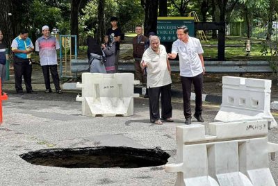 Fahmi (kanan) meninjau kejadian lubang benam di Taman Sri Nibong yang berlaku pada Rabu.