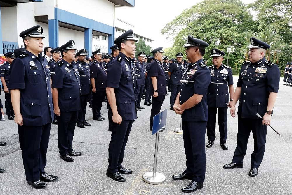 Razarudin (dua dari kanan) berkata sesuatu kepada seorang pegawai PDRM pada Perhimpunan Bulanan Ketua Polis Negara bagi bulan Oktober di Ibu Pejabat Polis Bukit Aman, Kuala Lumpur pada Jumaat. - Foto: PDRM.