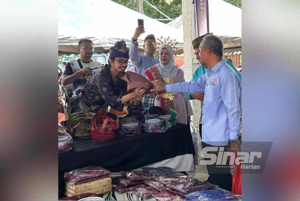 Mohamad Edry Sham (kiri) menunjukkan tanjak yang dihasilkan.