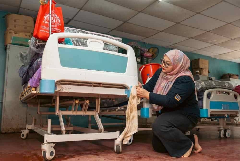 Kakitangan membersihkan katil yang terkesan akibat banjir.