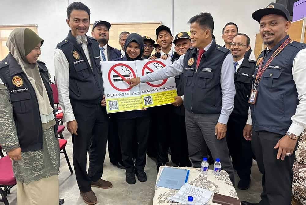 Dr Zaini (dua dari kanan) menunjukkan papan tanda larangan merokok yang baharu.