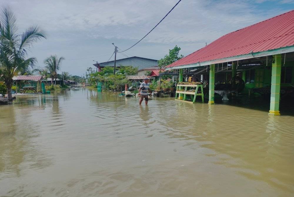 Penduduk meredah air pasang di Kampung Sungai Ayam Batu Pahat.