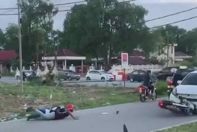 Tangkap layar memaparkan penunggang motosikal yang melakukan aksi 'wheelie' sambil membonceng seorang wanita sehingga terjatuh dan kemudian terlanggar hadapan sebuah kereta.