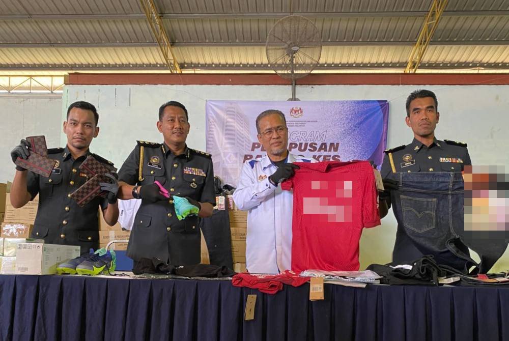 Azman (dua dari kanan) melupuskan sebahagian daripada barangan rampasan dengan menggunting.