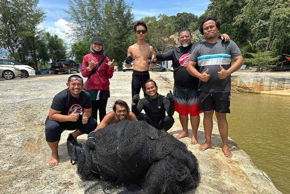 Shafuan (dua dari kanan) bersama kumpulan penyelam yang berjaya membawa naik pukat hantu seberat lebih 100 kg ketika aktiviti pembersihan dasar laut di perairan Pulau Tenggol, baru-baru ini.