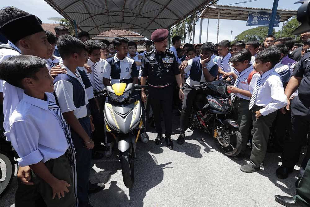 Mohd Yusri (tengah) beramah mesra dengan pelajar pada program Advokasi Kesedaran Keselamatan Jalan Raya di SMK Anderson, Ipoh.
