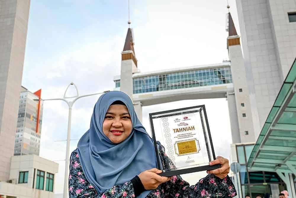 Pemenang, Suriani Sulleh, 30, menunjukkan Gold Bar yang diterima pada Majlis Pengurniaan Hadiah Kepada Pemenang Pengunjung Drawbridge Yang Ke Setengah Juta di sini, pada Jumaat. Foto Bernama