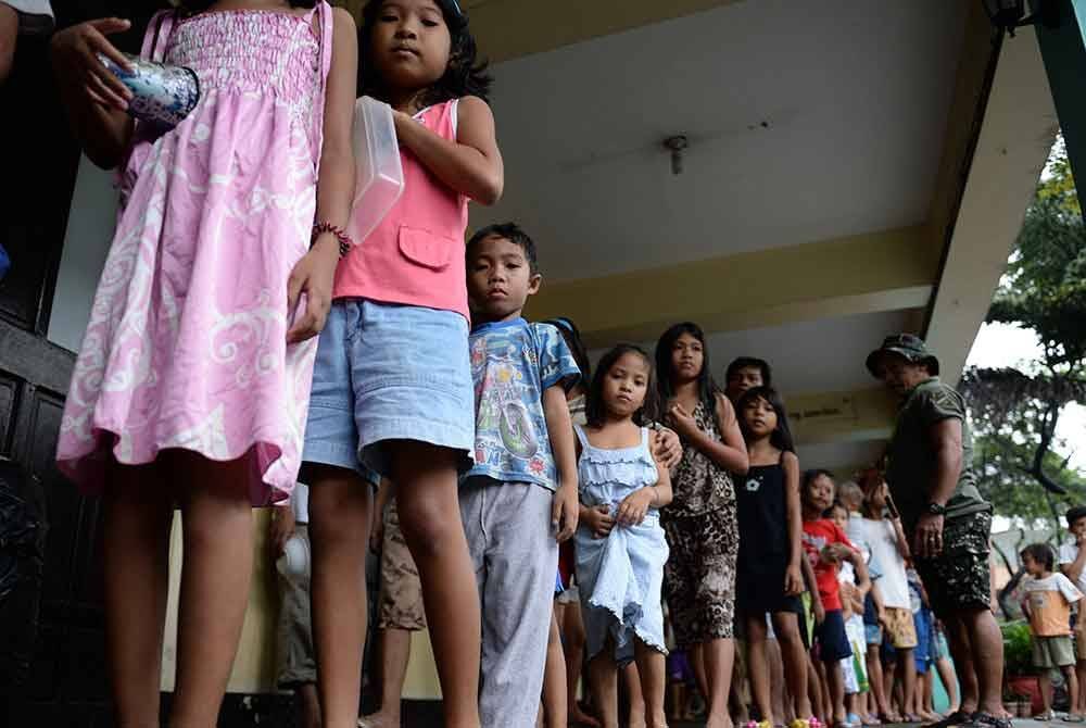 Kanak-kanak yang terjejas akibat Trami beratur untuk menerima makanan percuma diagihkan di kawasan penempatan sementara di Marikina, timur Manila.