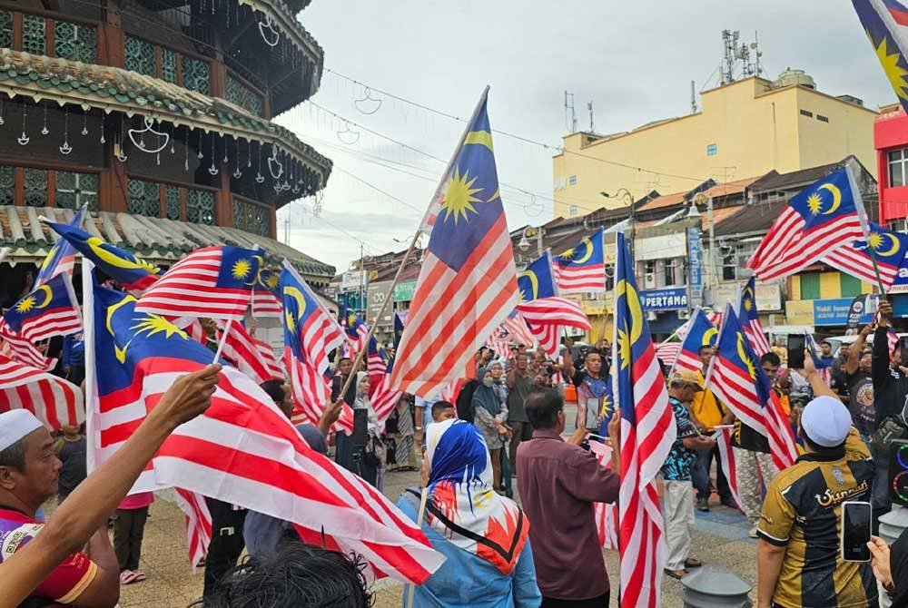 Orang ramai berkumpul di Dataran Menara Condong Teluk Intan menyokong usaha mengibarkan Jalur Gemilang susulan isu pengibaran bendera negara China dalam sambutan Guan Gong Sedunia, Khamis lalu.
