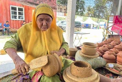 Zainab menunjukkan proses melicin dan memampatkan tembikar.