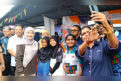 Fadhlina (kiri) bergambar bersama pelajar yang menghadiri Karnival Pendidikan Madani dan Program Kolej Vokasional Insani Masyarakat Madani di Sekolah Kebangsaan Sungai Bakap pada Sabtu.