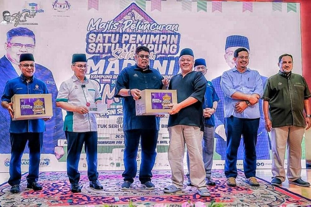 Pemangku Ketua Pegawai Eksekutifnya, Datuk Mohd Nizam Yahya (kiri) mengiringi Ketua Menteri, Datuk Seri Ab Rauf Yusof (tiga, kiri) dan Menteri di Jabatan Perdana Menteri (Hal Ehwal Agama), Datuk Dr Mohd Nai'im Mokhtar (dua, kiri) menyampaikan bantuan bakul makanan kepada salah seorang asnaf pada Majlis Perasmian Peluncuran Satu Pemimpin Satu Kampung (Santuni MADANI) di Kampung Balik Batu, Tanjung Bidara, Alor Gajah, pada Sabtu.