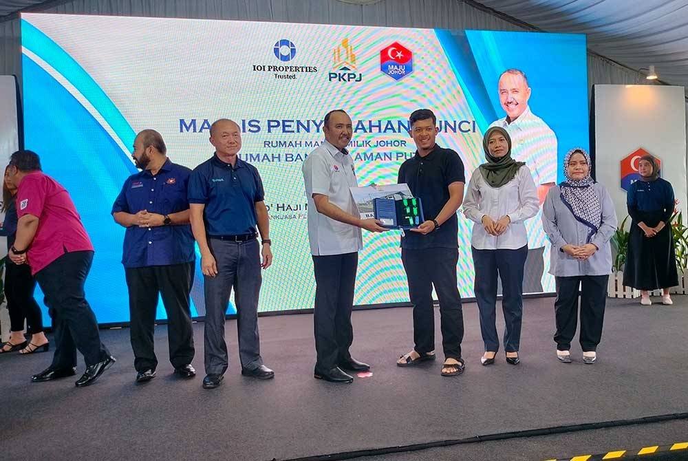 Mohd Jafni (empat dari kiri) menyerahkan kunci kepada pemilik RMMJ di Bandar Putra, Kulai pada Ahad.