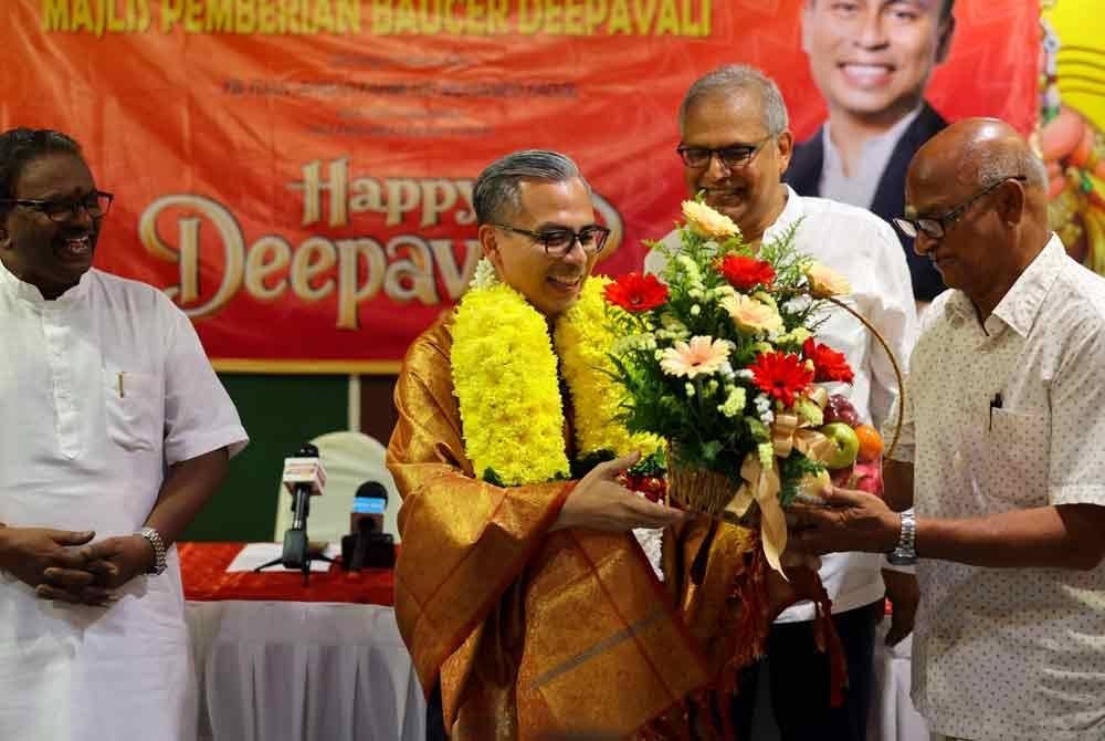 Fahmi menerima jambangan bunga tanda penghargaan daripada Pengerusi Persatuan Pengurusan Kuil Arulmigu, Valautham (kanan) pada majlis Pemberian Baucar Deepavali kepada 300 penerima di kawasan Parlimen Lembah Pantai pada Ahad. Foto Bernama