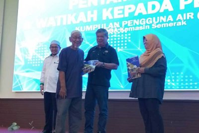 Mohamad (dua, kanan) menyampaikan watikah kepada ketua tani pada Ahad.