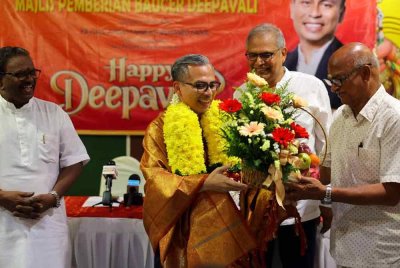 Fahmi menerima jambangan bunga tanda penghargaan daripada Pengerusi Persatuan Pengurusan Kuil Arulmigu, Valautham (kanan) pada majlis Pemberian Baucar Deepavali kepada 300 penerima di kawasan Parlimen Lembah Pantai pada Ahad. Foto Bernama