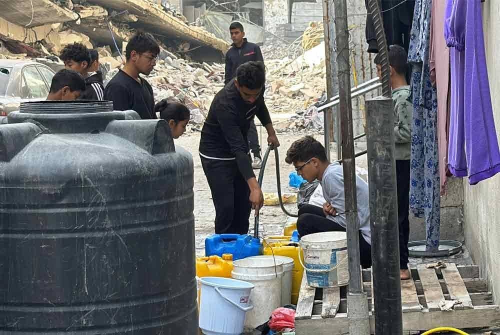 Penduduk Palestin beratur menunggu giliran untuk mengisi bekalan air bersih di Beit Lahia, utara Gaza.
