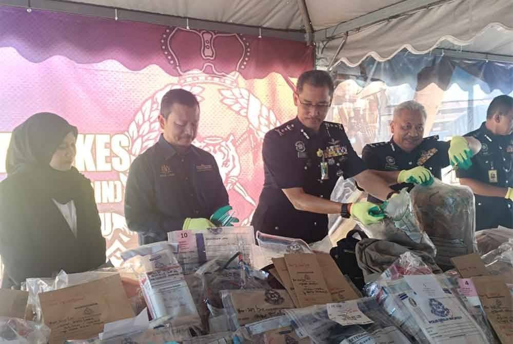 Mohd Khairi (tengah) memeriksa barang jenayah dilupuskan di pekarangan Ibu Pejabat Polis Kontinjen Terengganu pada Isnin.