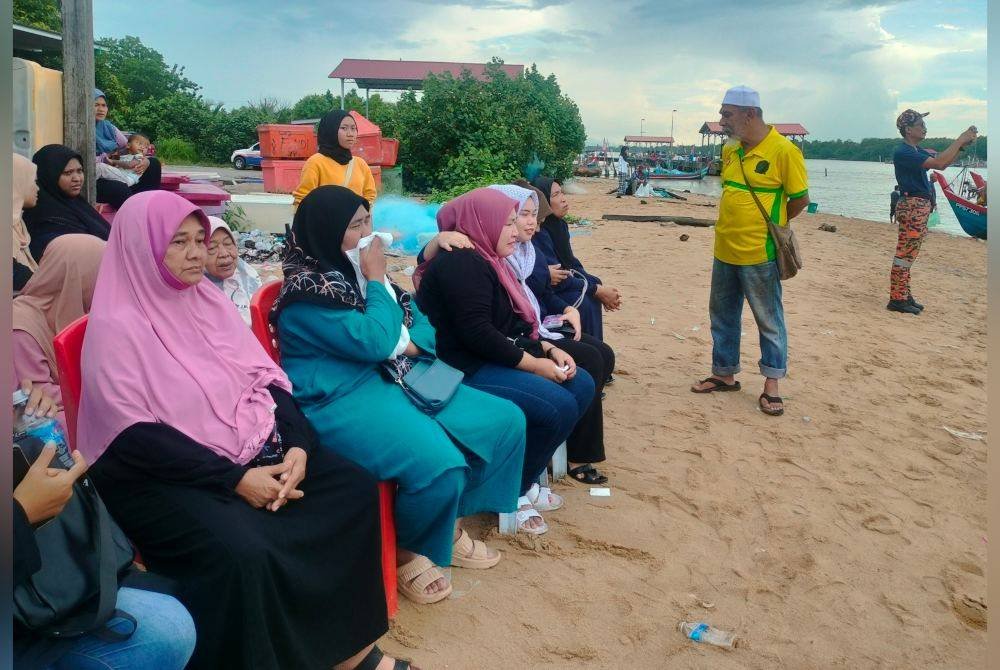 Dua dari kiri: Rosnah dan Nur Farhana setia menunggu operasi mencari dan menyelamat Muhamad Aiman Safwan Mahadzir yang dikhuatiri lemas.