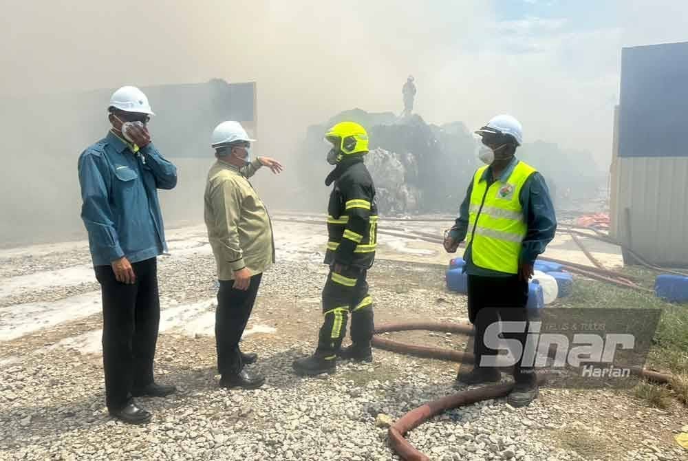 Mohamad Zamzani (kiri) dan Hilmi (dua dari kiri) menggunakan topeng muka ketika melawat tempat kejadian di Kawasan Perindustrian Pengkalan Chepa 2, Kota Bharu.