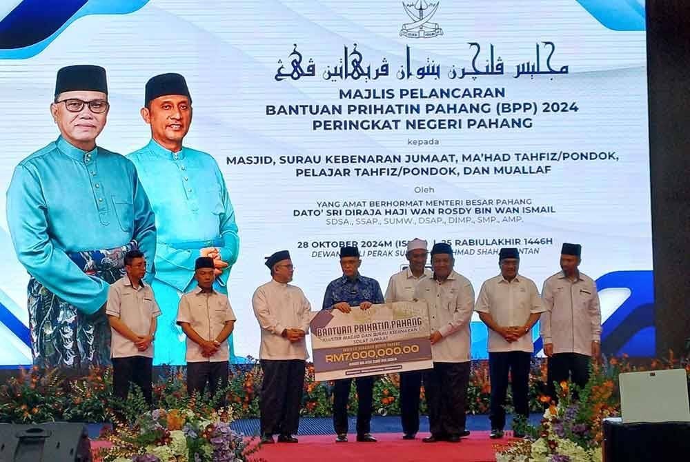 Wan Rosdy (tengah) menyampaikan replika cek kepada penerima daripada kluster masjid dan surau kebenaran Jumaat pada majlis pelancaran Bantuan Prihatin Pahang 2024 di Dewan Jubli Perak Sultan Haji Ahmad Shah pada Isnin.