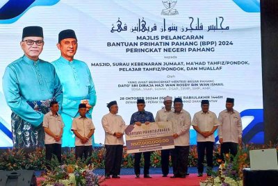 Wan Rosdy (tengah) menyampaikan replika cek kepada penerima daripada kluster masjid dan surau kebenaran Jumaat pada majlis pelancaran Bantuan Prihatin Pahang 2024 di Dewan Jubli Perak Sultan Haji Ahmad Shah pada Isnin.