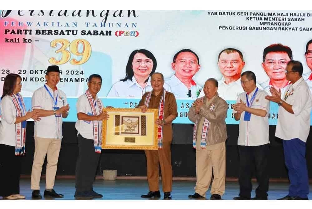 Hajiji menerima cenderamata daripada Joachim ketika merasmikan Persidangan Perwakilan Tahunan PBS Ke-39 di Dewan Hongkod Koisaan, KDCA, Penampang.