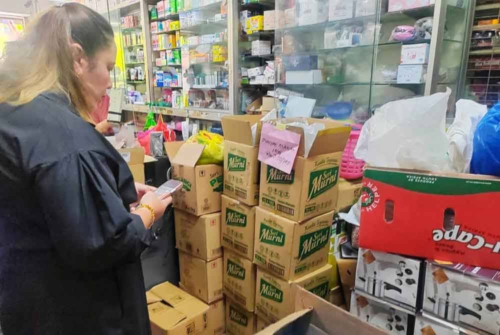 Norena (kiri) melihat lebih 10 kotak minyak masak bersubsidi yang ditemui dan dirampas dalam sebuah kedai runcit di Taman Mewah, di Melaka, pada Selasa.