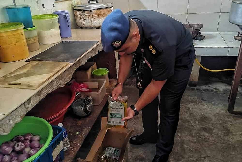 Pegawai penguat kuasa menunjukkan beberapa minyak masak peket yang dijumpai di sebuah kedai makan diuruskan warga asing.