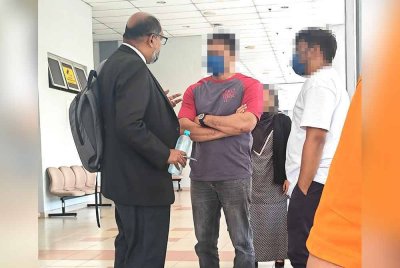 Tertuduh (tengah) bertemu dengan peguam di luar mahkamah.