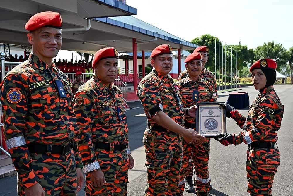 Nordin (tiga dari kiri) menyampaikan Anugerah Pelatih Terbaik, Saredah (kanan) pada Majlis Tamat Latihan Kursus Asas Pasukan Khas Operasi, Taktikal dan Penyelamat Malaysia (STORM) JBPM Siri 1/2024 di Akademi Bomba dan Penyelamat Malaysia Wilayah Timur, Wakaf Tapai, pada Rabu. Foto Bernama